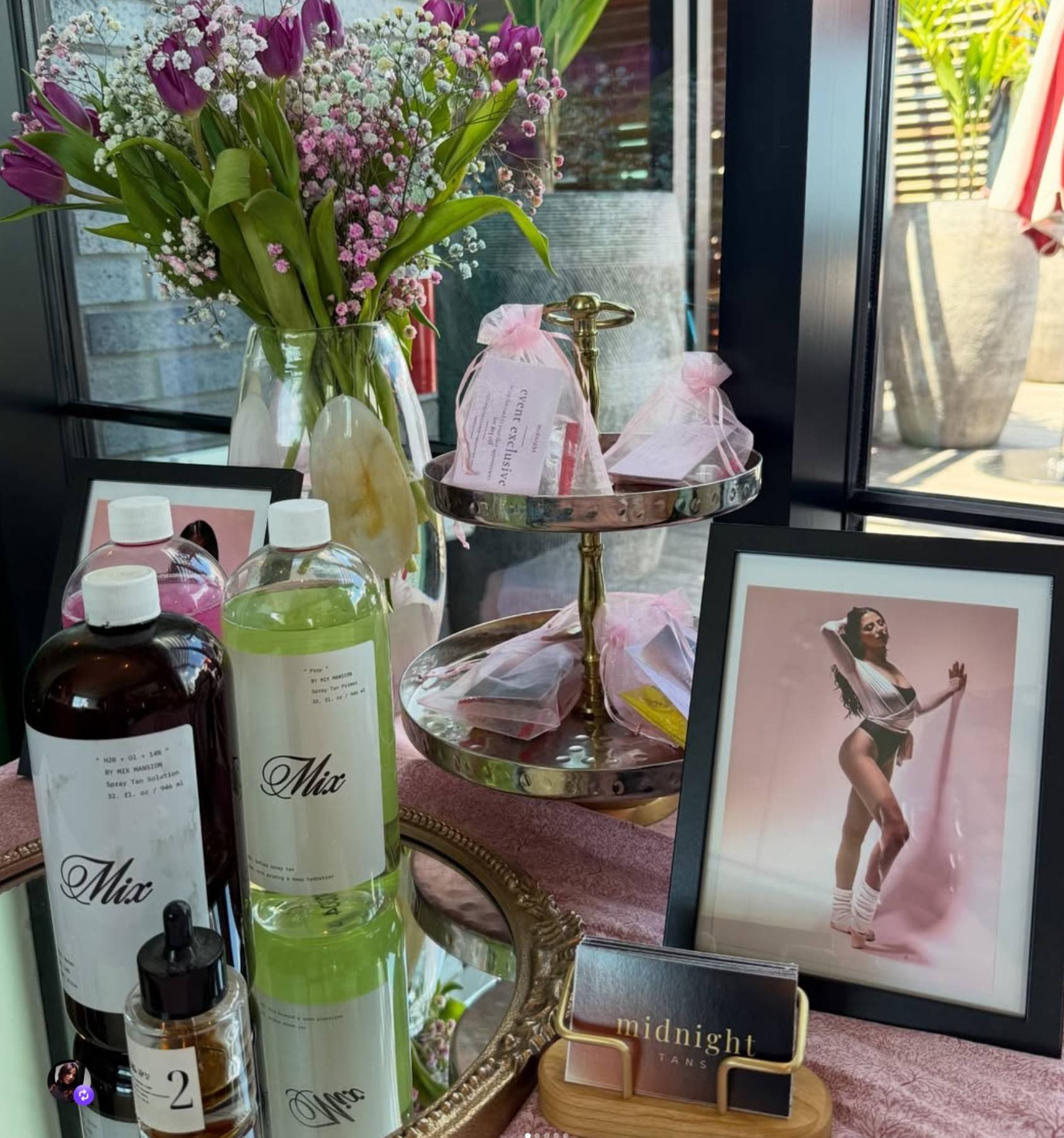 olivia's mobile spray-tan kit set out on a table with solution bottles, flowers and a framed print