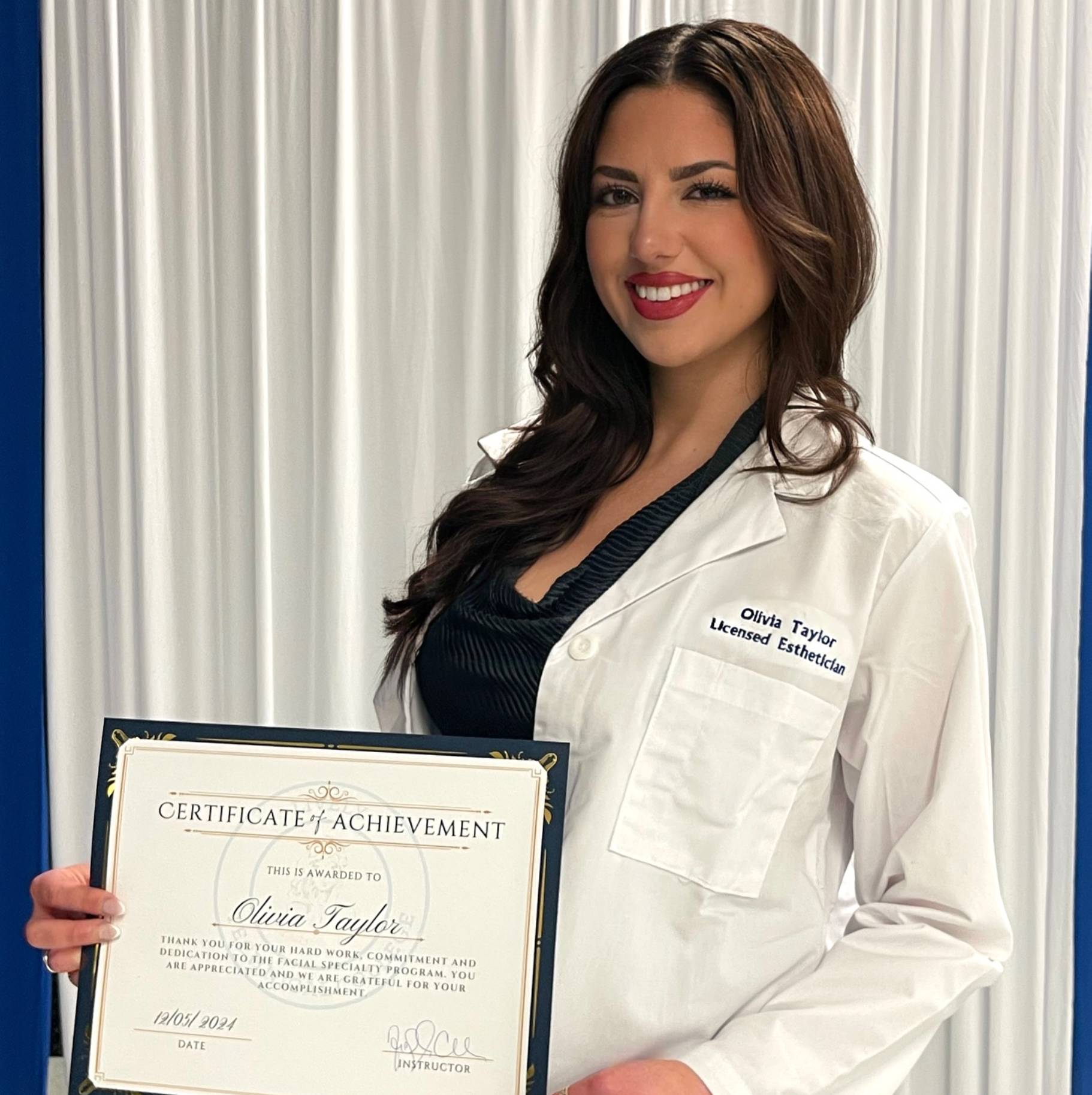 olivia taylor in her white esthetician coat, holding her certificate of achievement